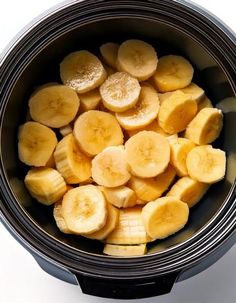 sliced bananas in a slow cooker on a white table top, ready to be cooked