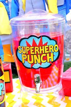 there is a cup with the name superhero punch on it and some legos in the background