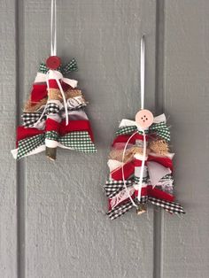 two christmas tree ornaments hanging from hooks on a door with ribbons and buttons attached to them