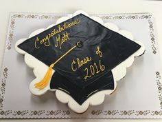 a decorated graduation cake on top of a white plate with gold lettering and a tassel