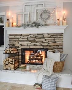 a fireplace with candles and blankets on it in front of the fire place filled with logs