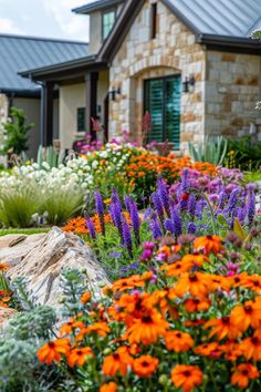 an assortment of flowers in front of a house