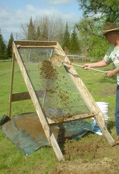 a man is shoveling dirt into a garden bed