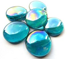 six blue and green glass cabochons sitting on top of a white countertop