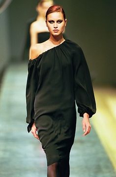 a woman walking down a runway in a black dress