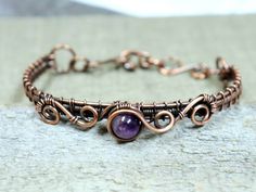 a copper bracelet with an amethorate bead and wire work on it