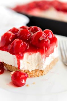 a piece of cheesecake topped with cherries on a plate next to a fork