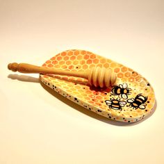 a wooden spoon with a honey comb and bees on it sitting on a white surface