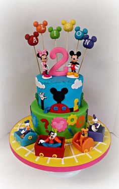 a birthday cake with mickey mouse toppers and decorations on it's sides, including the number two