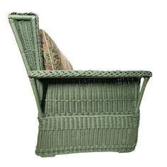 a green wicker chair sitting on top of a white floor next to a pillow