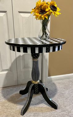 a vase with sunflowers sitting on top of a black and white striped table