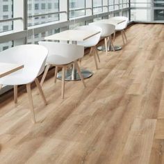 a row of white chairs sitting next to each other on top of a wooden floor