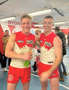 two men standing next to each other in red and white uniforms holding tennis racquets