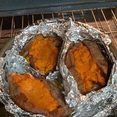 three baked sweet potatoes sitting on tin foil in an oven, with one being cooked