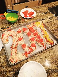 a homemade pizza with pepperoni and cheese on a baking sheet next to other ingredients