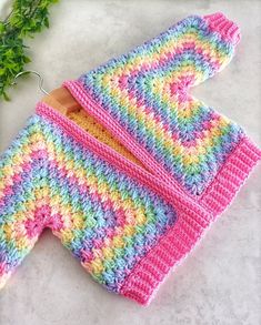 two crocheted mittens sitting on top of a white counter next to a plant