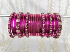 The perfect fusion of tradition and style, designed to elevate your outfit with elegance and charm. This stunning bangle set offers the versatility you've been searching for, as it can be tailored to adorn either one hand or both, ensuring that you shine in any setting. This set includes a total of 24 colored bangles, carefully selected to complement a wide range of outfits and moods. 2 stunning Kara bangles add a touch of mystique and allure to your ensemble, and 4 Churi bangles provide a captivating contrast to your look. To maintain a balance we've also included 11 plain insert bangles, offering a clean and classic finish to your overall aesthetic. Purple Bangle For Wedding, Adjustable Pink Bracelet For Diwali, Traditional Purple Bracelets For Festivals, Traditional Purple Bracelets For Festive Occasions, Traditional Purple Bracelet For Festive Occasions, Adjustable Purple Bangle For Festive Occasions, Traditional Adjustable Purple Bangle, Traditional Purple Bangle Bracelets, Purple Bangle Bracelets For Festivals