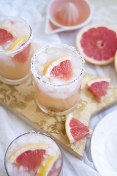 grapefruit cocktails are served on a cutting board with slices of lemon and grapefruit