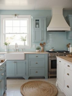 a kitchen with blue cabinets and white counter tops, an area rug on the floor