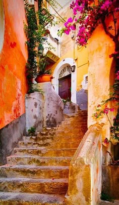 the stairs lead up to an old building with pink flowers growing on it's sides