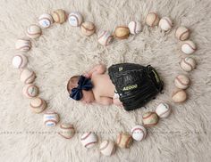 a baby laying on top of a pile of baseballs