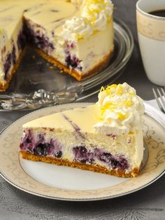 a slice of lemon blueberry cheesecake on a plate next to a cup of coffee