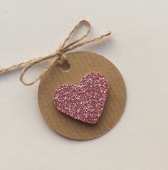 a heart shaped ornament hanging from a string on top of a brown tag