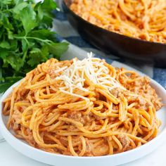 spaghetti with meat sauce and parmesan cheese in a white bowl on a table