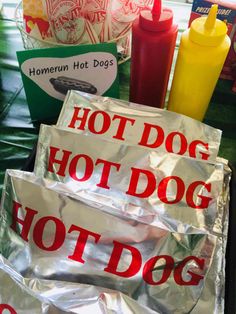 hot dog buns are wrapped in foil and sitting on a table next to condiments