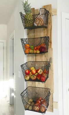 three metal baskets filled with fruit on top of a wooden wall hanging from the side of a door