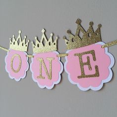 pink and gold first birthday banner with crown on top, one sign hanging from the line