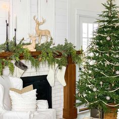 a living room decorated for christmas with white furniture and green garland on the mantel