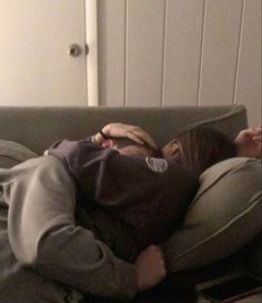 a man laying on top of a couch next to a woman in a gray shirt