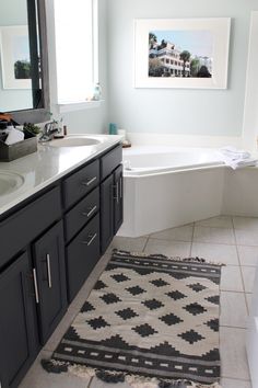 a bathroom with a bathtub, sink and rug on the floor in front of it