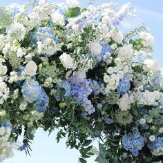 blue and white flowers are arranged in the shape of an arch