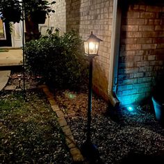 a lamp post in front of a brick building at night with the light turned on