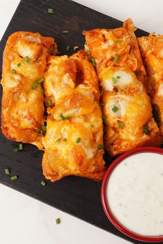 some food is on a black tray and next to a small bowl of ranch dressing