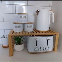 there is a toaster, kettle and cups on the shelf next to the coffee pot