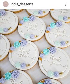 decorated cookies with the words thank you and blue flowers are arranged in rows on a table