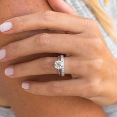 a woman's hand with a diamond ring on her finger and an engagement band