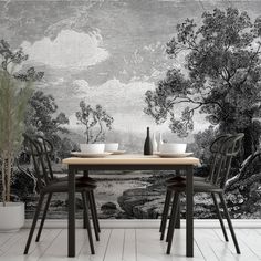 a dining table with two chairs in front of a wallpapered mural that has trees on it