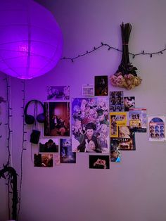 a room with purple lighting and many pictures on the wall next to a vase filled with flowers