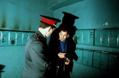 two men in uniform standing next to each other near lockers with boxes on them