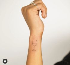 a woman's arm with a wine glass tattoo on her left wrist and the word love written in it