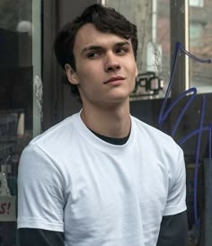 a young man standing in front of a store window