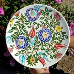 a plate with flowers painted on it being held by someone's hand