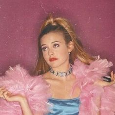 a woman in a blue dress with pink feathers on her shoulders and arms, posing for the camera