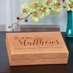 a wooden box sitting on top of a table next to a vase filled with flowers