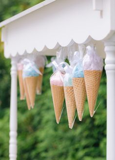 three cones filled with ice cream sitting on top of a white table next to trees