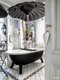 a bathtub sitting under an umbrella in a bathroom